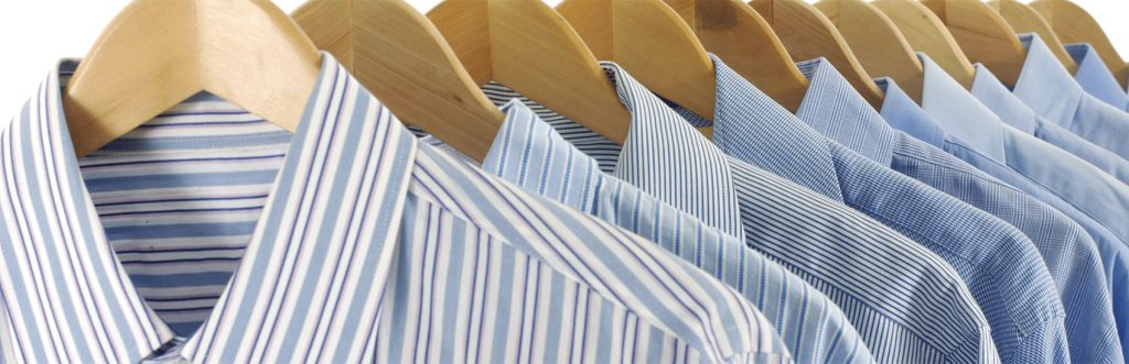 Row of men's dress shirts on wooden hangers